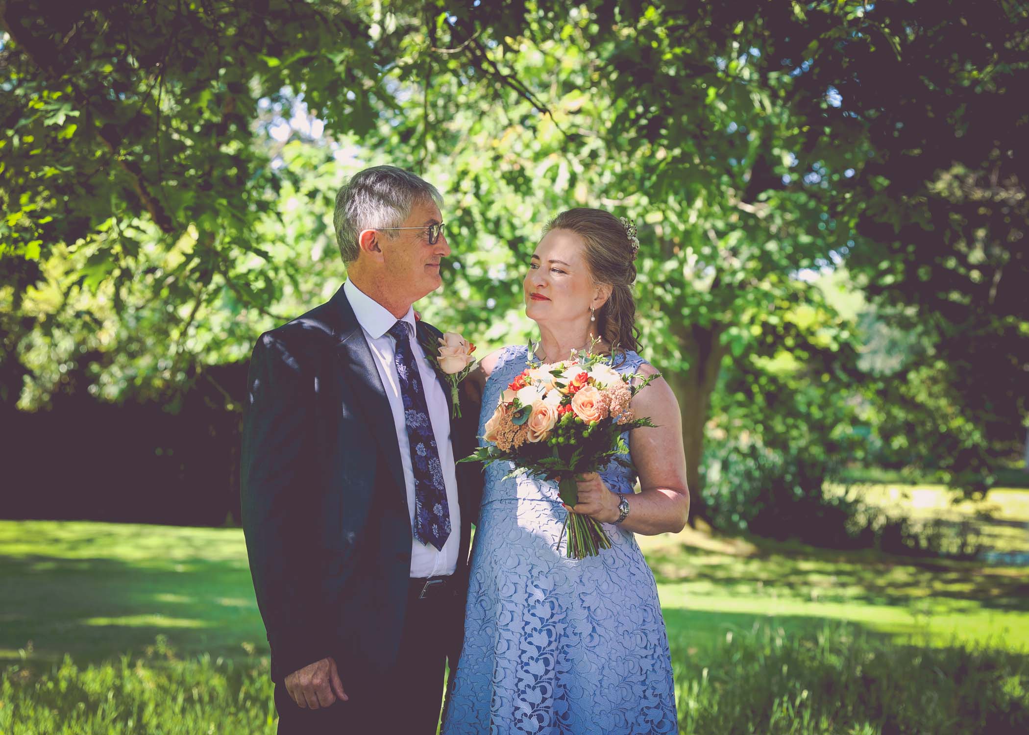 A bride and groom looking at each other under an oak tree on a wedding day in Woodbridge captured by Suffolk Wedding Photographer Hayley Denston Photography